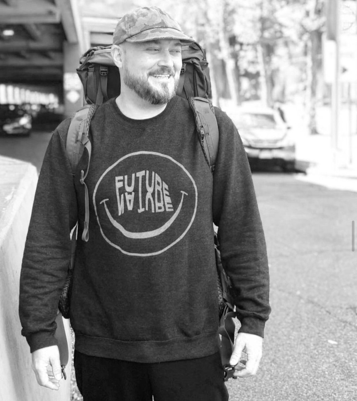 David Gensler wearing a Future Nature sweatshirt, camouflage cap, and hiking backpack in a black-and-white outdoor portrait.