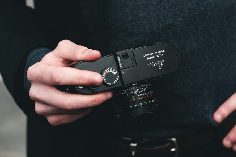 a Leica M rangefinder camera held by hand, photographed by Steven Roussel.