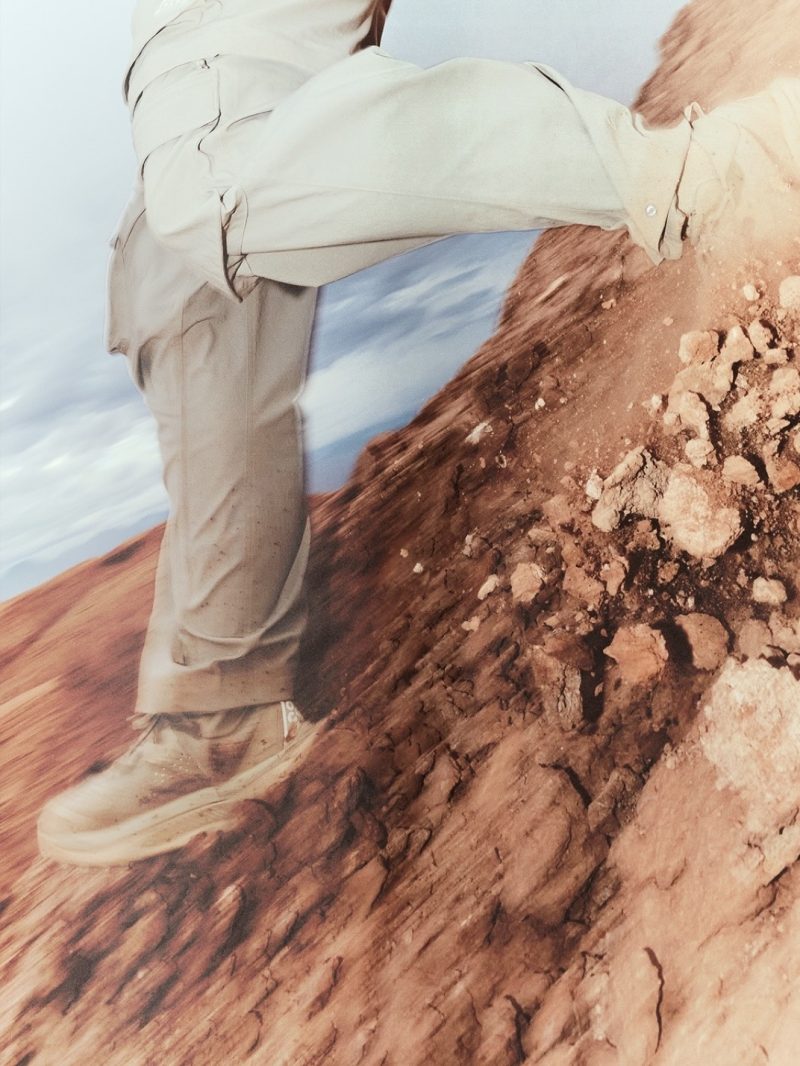 Nike ACG technical pants and trail footwear climbing across rocky red terrain.
