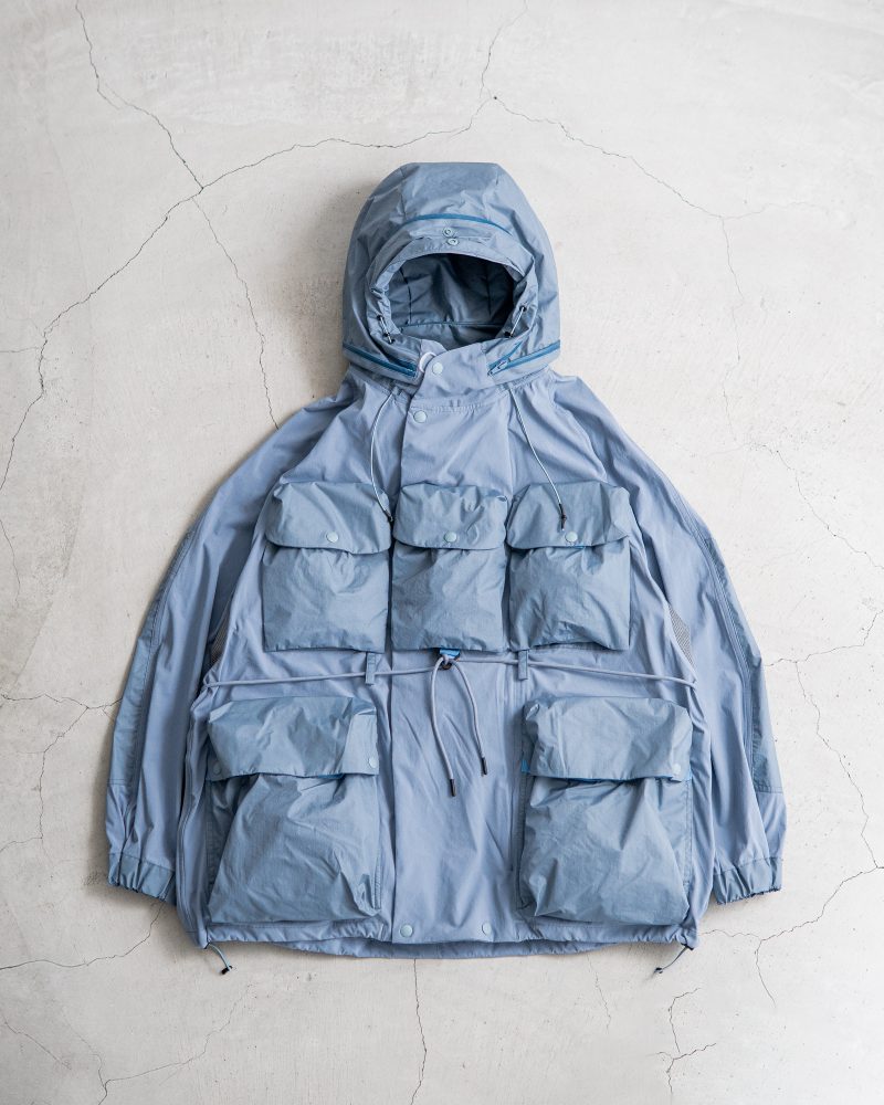 David Gensler outdoor style reference showing a pale blue norbit technical jacket with oversized utility pockets and an adjustable hood.
